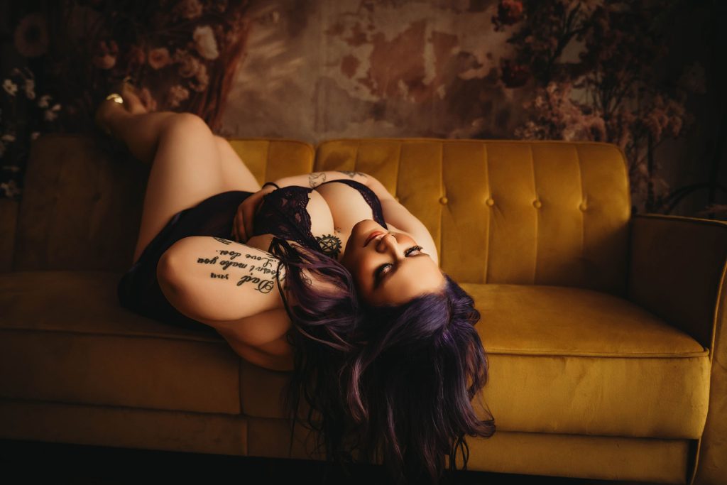 Dark and moody boudoir portrait of curvy woman with purple hair
