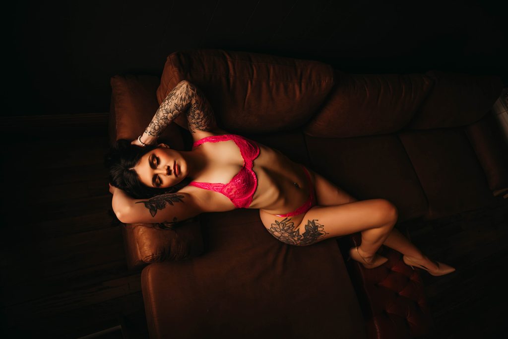 Dark and moody portrait of petite tattooed woman with pink lingerie